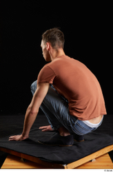 Alessandro Katz  black shoes blue jeans brown t shirt casual dressed kneeling whole body  jpg